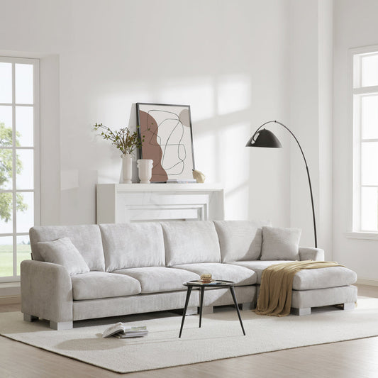 Modern oversized L-shaped sectional sofa with chaise and two pillows in a bright living room setting.
