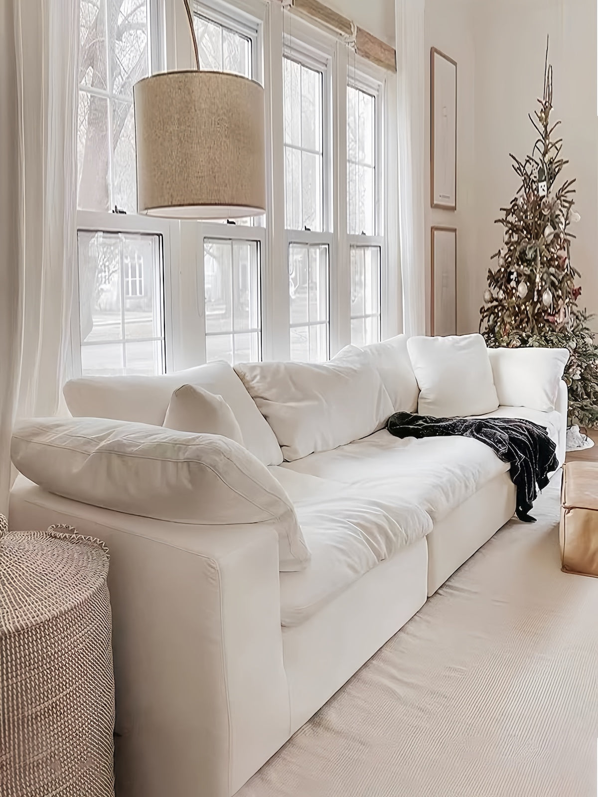 White cotton couch in living room with a Christmas tree and large windows.
