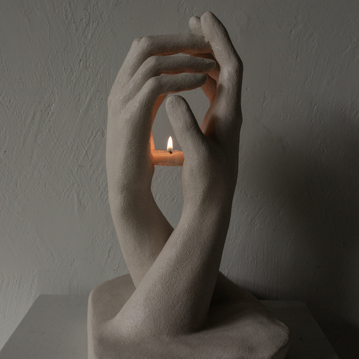 Handmade creative candlestick featuring two sculptural hands reaching toward each other with smooth curves and rustic matte texture in vintage French style