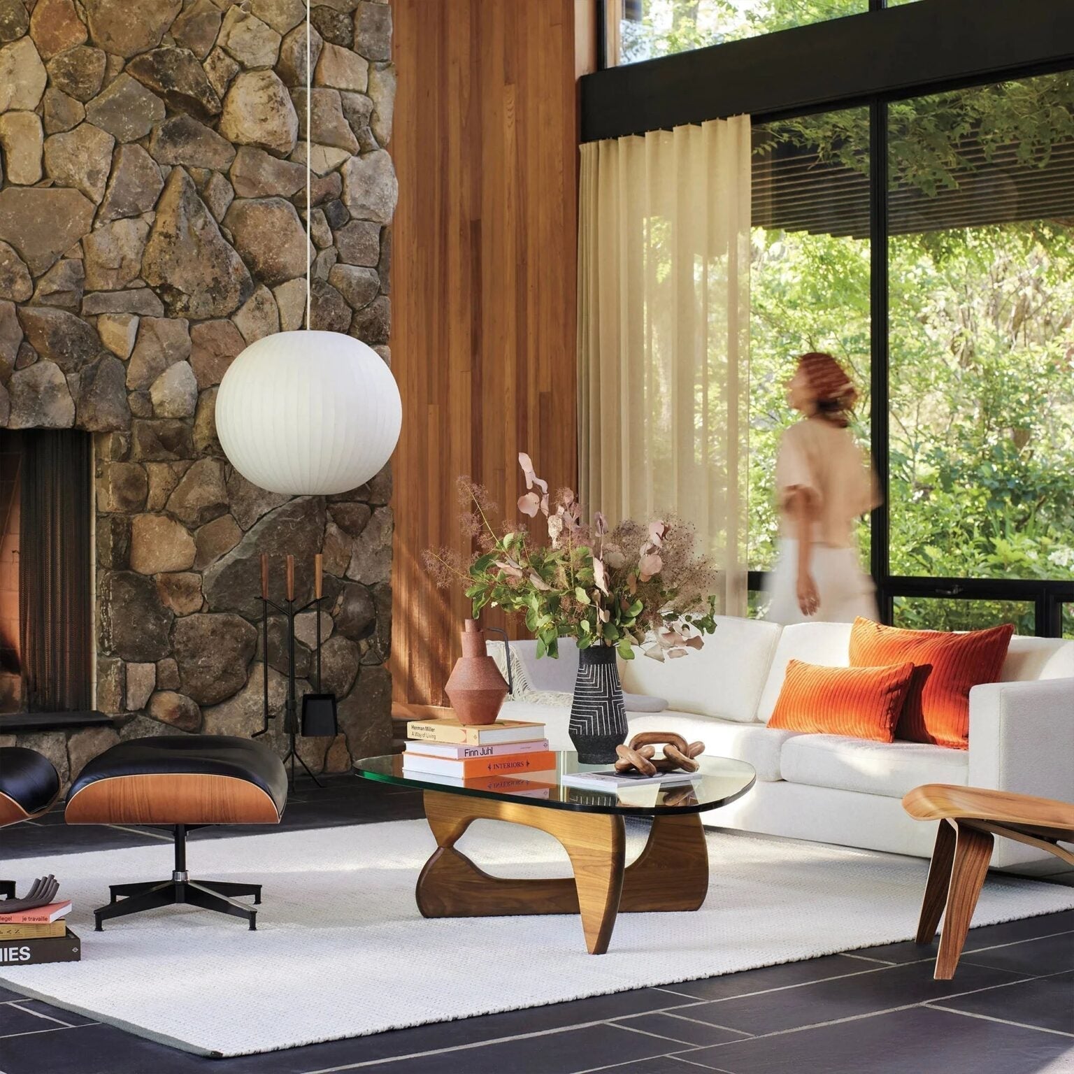 Noguchi Coffee Table in modern living room with stone fireplace and stylish furniture.