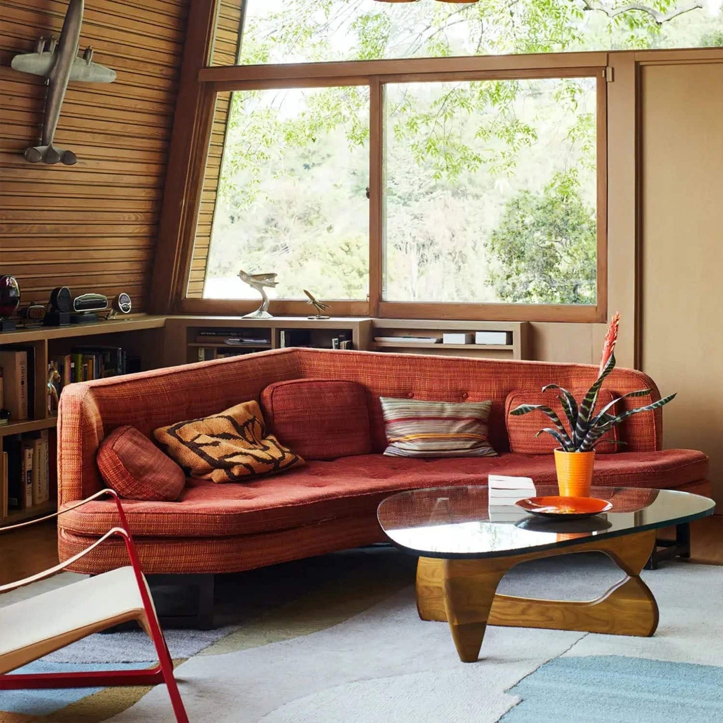 Noguchi Coffee Table in modern living room with sculptural wood base and clear glass top.