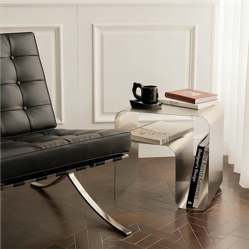 Minimalist stainless steel lounge side table with books and coffee mug.