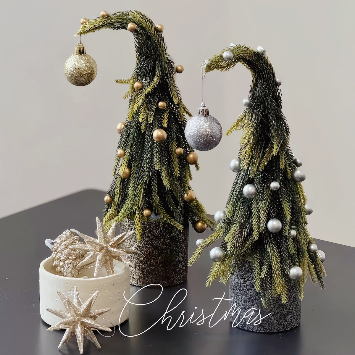Decorative Christmas trees with ornaments on a dark surface