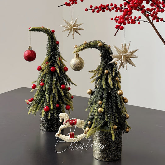 Decorative Christmas trees with ornaments on a dark surface