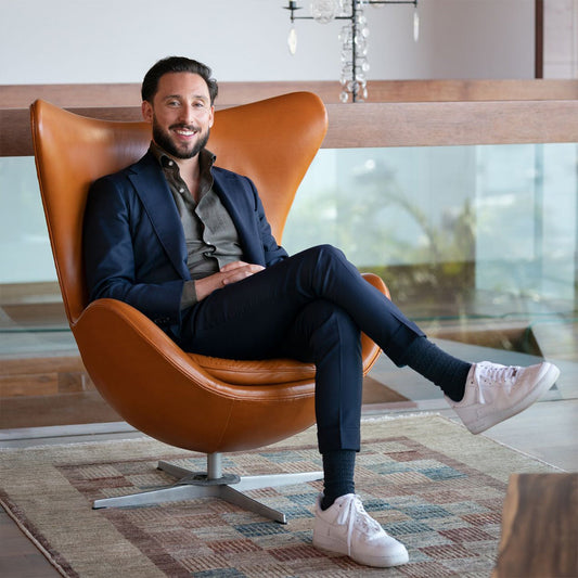 Brown egg chair with a man sitting comfortably, showcasing modern design and elegance.