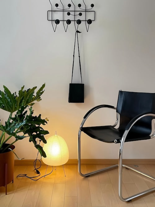 Traditional Japanese rice paper lamp illuminating modern interior space with wooden floor and chair.