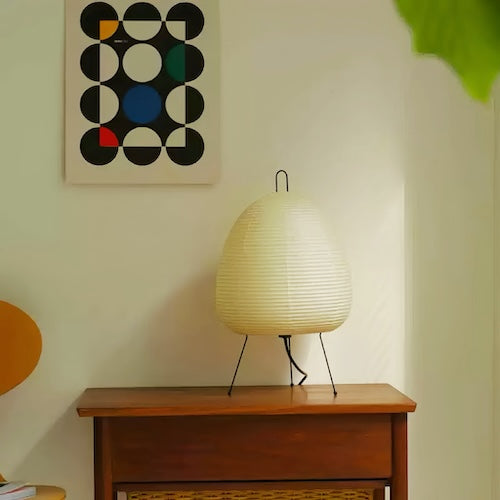 Traditional Japanese rice paper lamp on wooden table in minimalist room.