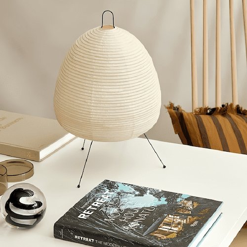 Traditional Japanese rice paper lamp on a table with books and decor.