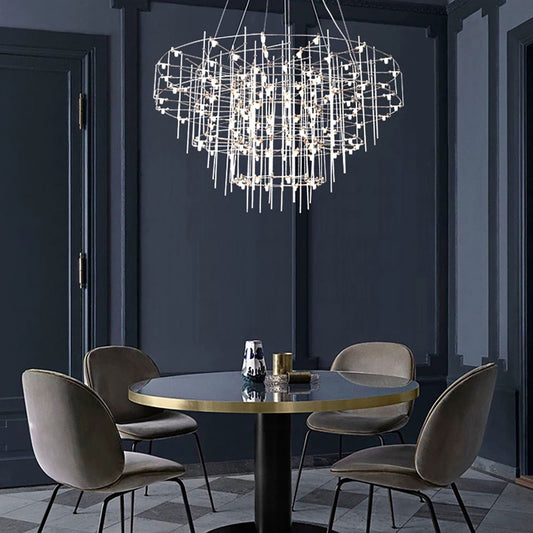 Modern chandelier hanging above a round dining table with four chairs in a darkly paneled room.