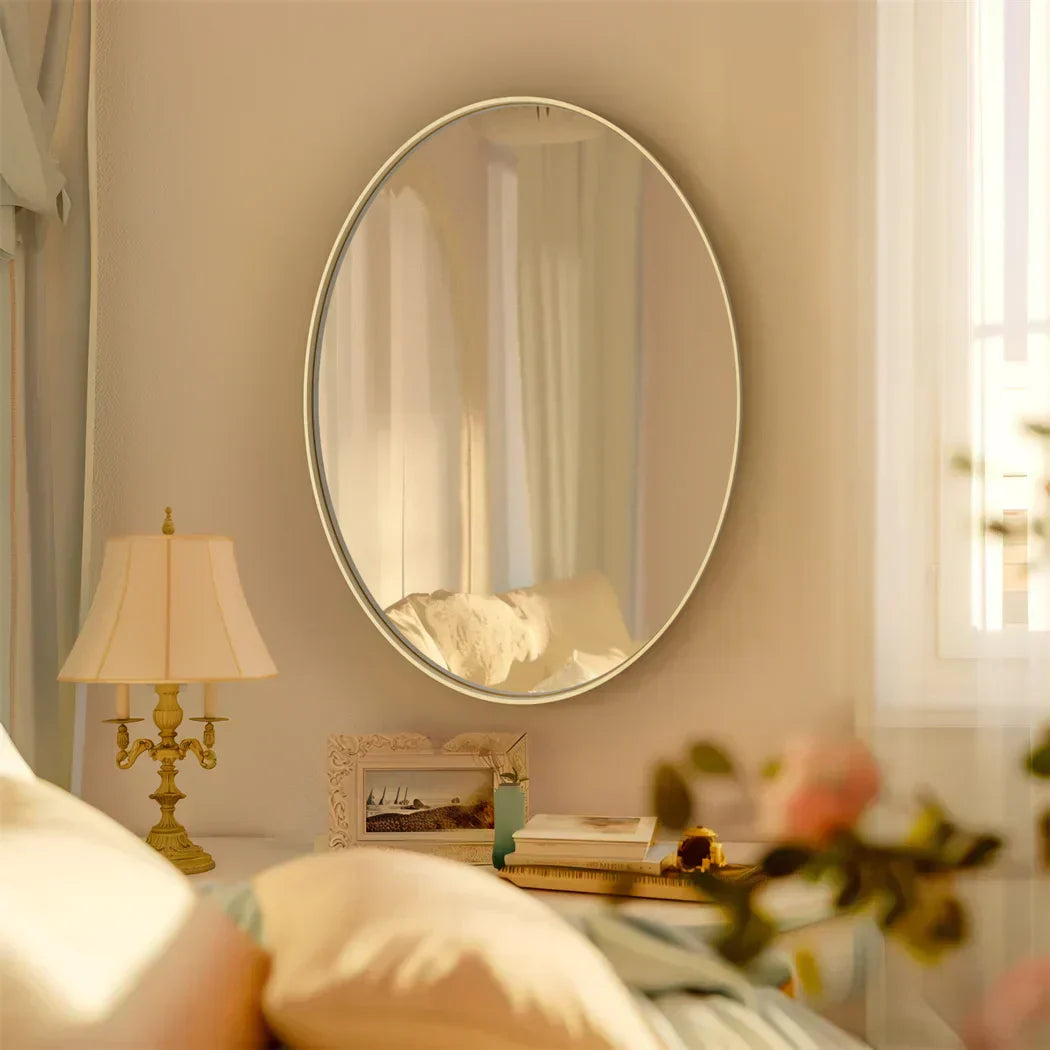 Oval vanity mirror with brushed gold frame, enhancing bedroom elegance.