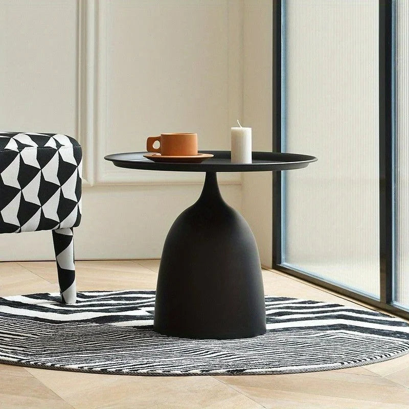 Contemporary round side table with sleek black metal design in modern living space.