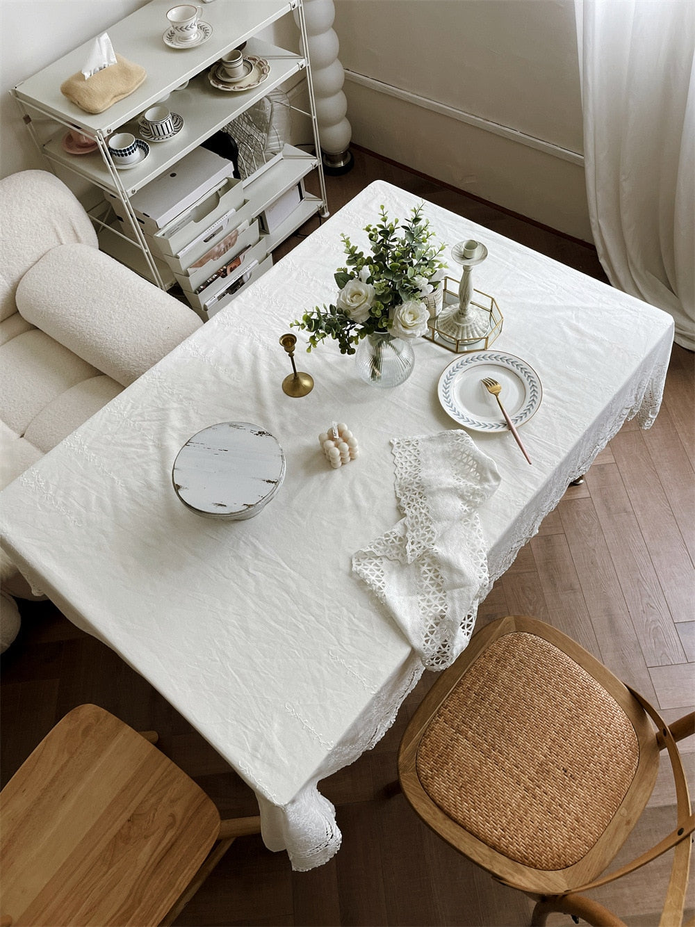 Elegant white tablecloth with intricate embroidery on a dining table, perfect for weddings and gatherings.