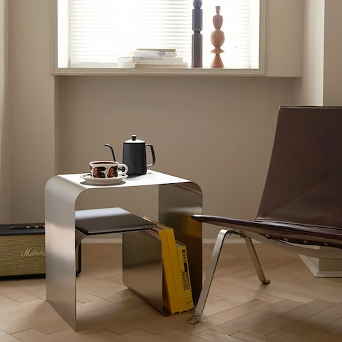 Minimalist stainless steel lounge side table in modern living room setting.