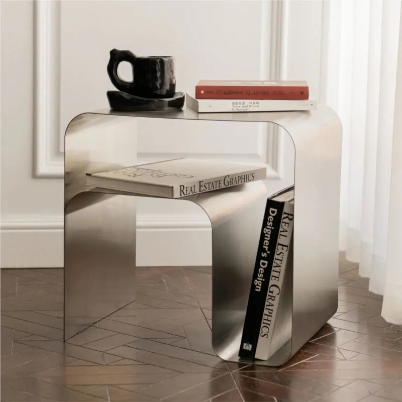 Minimalist Stainless Steel Lounge Side Table with books and a mug, seamless modern design.