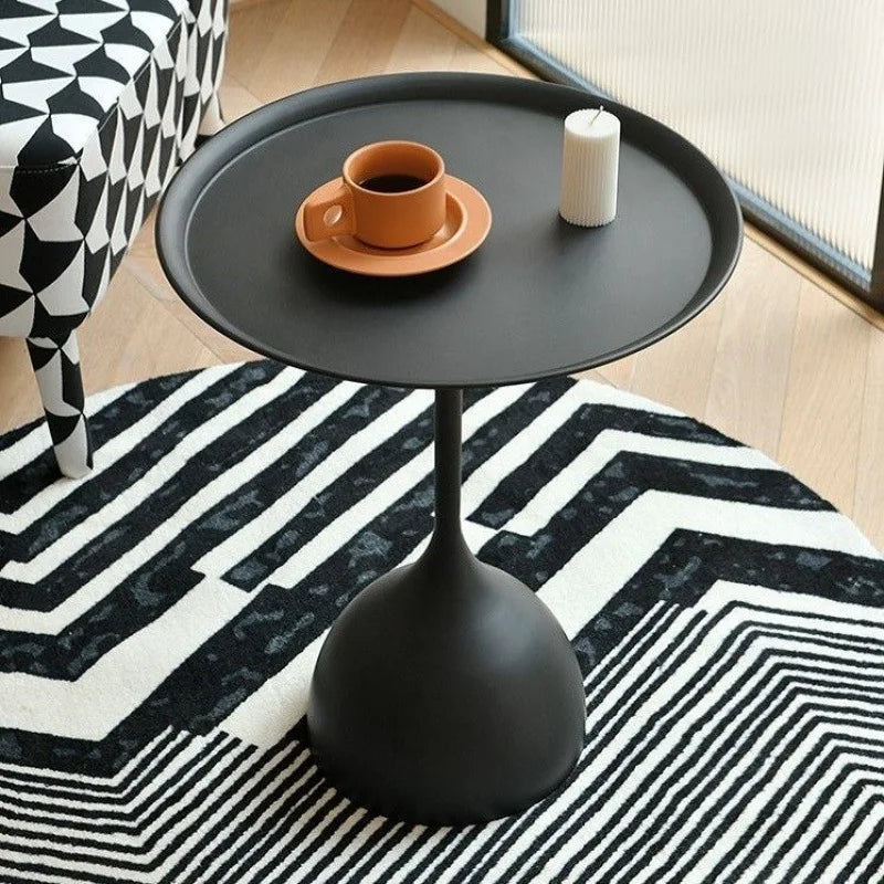 Contemporary round side table with black metal finish in modern living space.