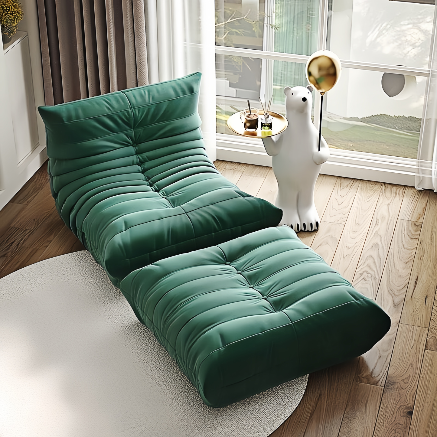 Togo Fireside Chair and Foot Stool in dark green suede upholstery, placed on a light rug with a decorative side table.