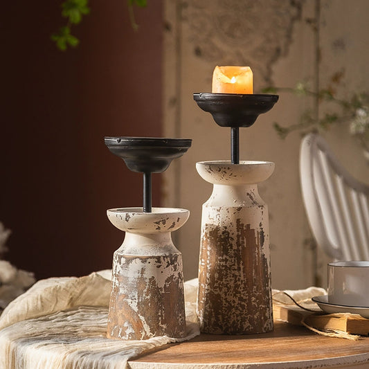 Two rustic candle holders with candles on a wooden surface.