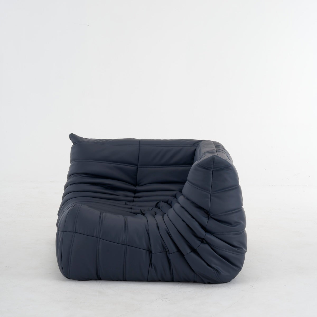 Togo Corner Sofa in black leather with distinctive ruched stitching and a low, curved silhouette.