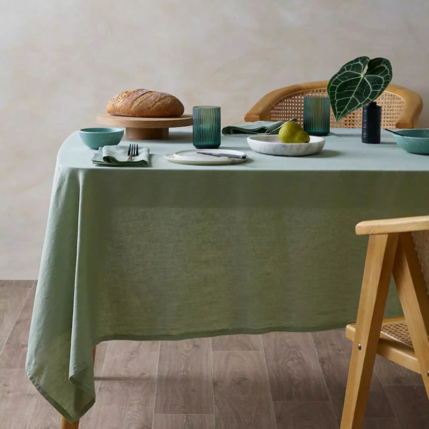 Rectangle tablecloth in vibrant green linen, draped over dining table with natural wood chair settings.