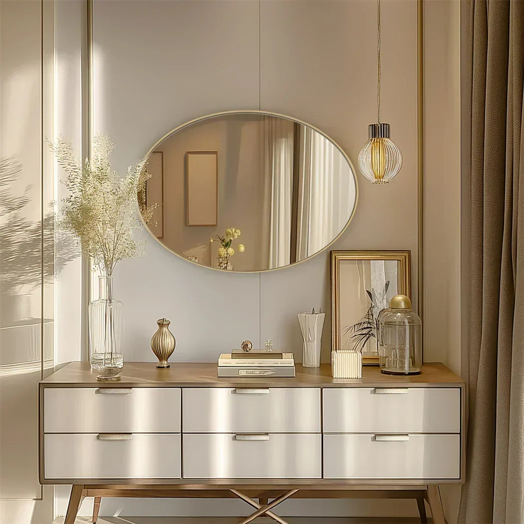 Elegant oval vanity mirror with gold aluminum frame in a stylish bedroom setting.