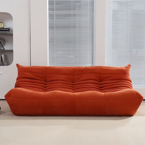 Ligne Roset Togo sofa in orange suede, featuring plush curved cushions and modern design.