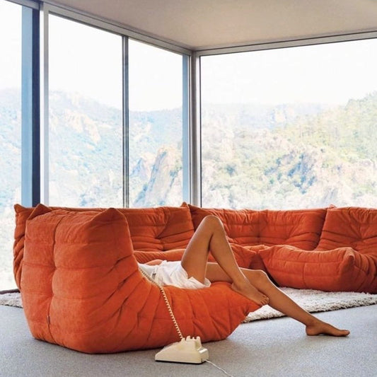 Modern orange corduroy Togo sofa set with view of mountains.