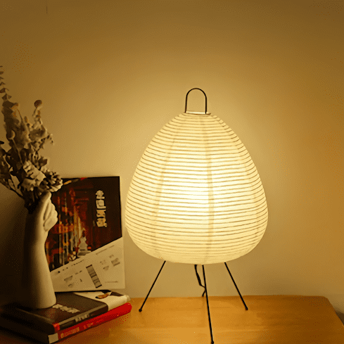 Traditional Japanese rice paper lamp with an iron tripod illuminated on a table, showcasing Wabi-sabi style and handmade craftsmanship.