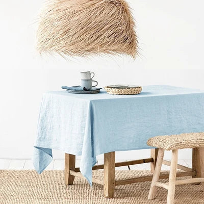 Sky blue rectangle tablecloth made of 100% pure linen, draped over a wooden table.