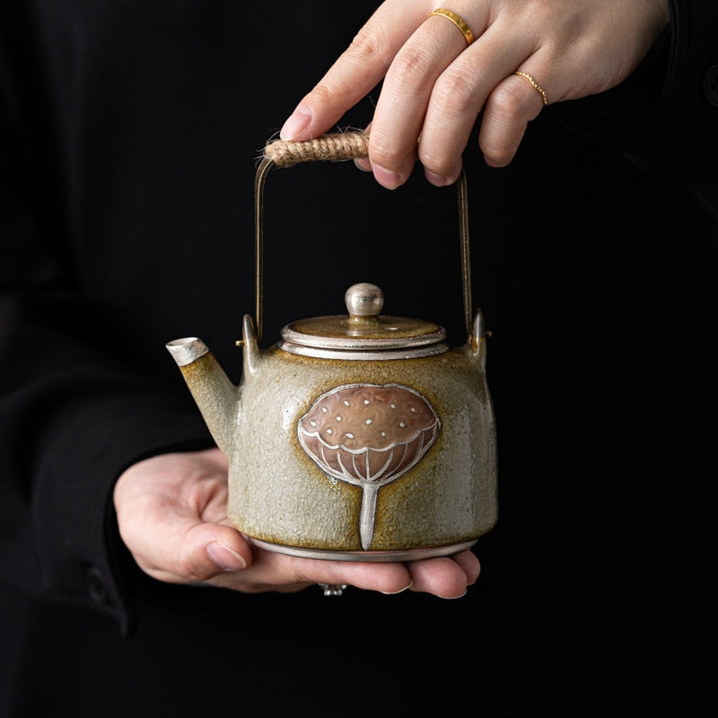 Ceramic teapot from the Tea Gift Set held by hands, showcasing intricate design and craftsmanship.