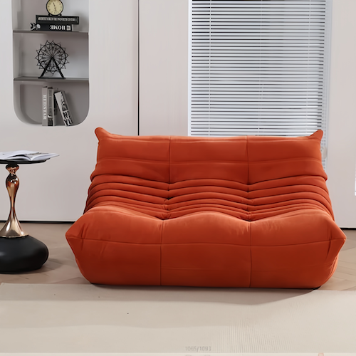 Ligne Roset Togo sofa in orange suede, showcasing its stylish design in a modern living room.