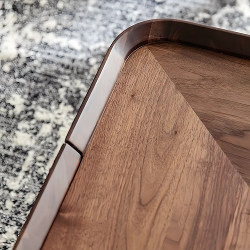 Square walnut coffee table with rounded edges on a textured rug.